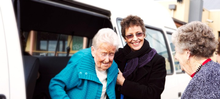 carer with elderly woman getting out of van