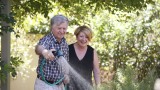 Female home care worker helping male Home Care Package client to water his garden